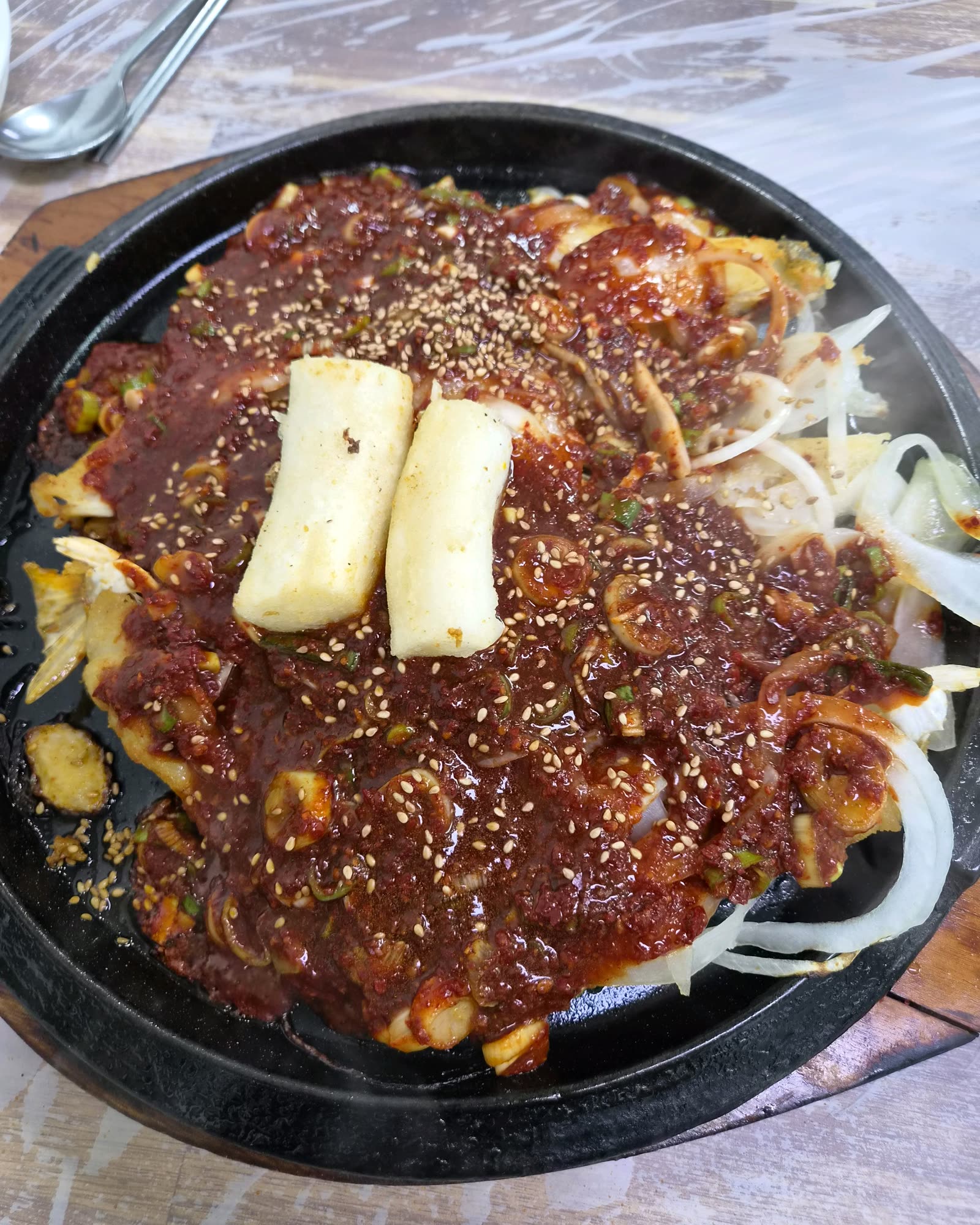 재진이네아구찜 동래본점 대구뽈구이 철판, 김이 오르는 매콤한 양념 대구뽈 위에 가래떡 사리가 올라간 모습