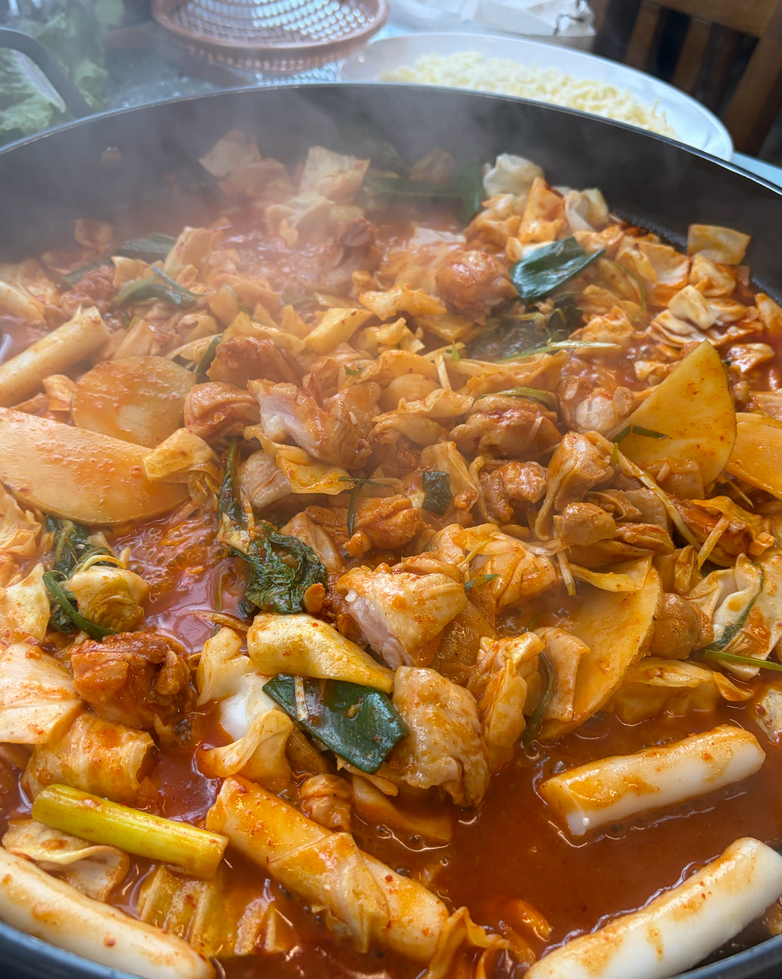 철판에서 김이 오르며 볶아지고 있는 풍장닭갈비의 닭갈비와 떡사리