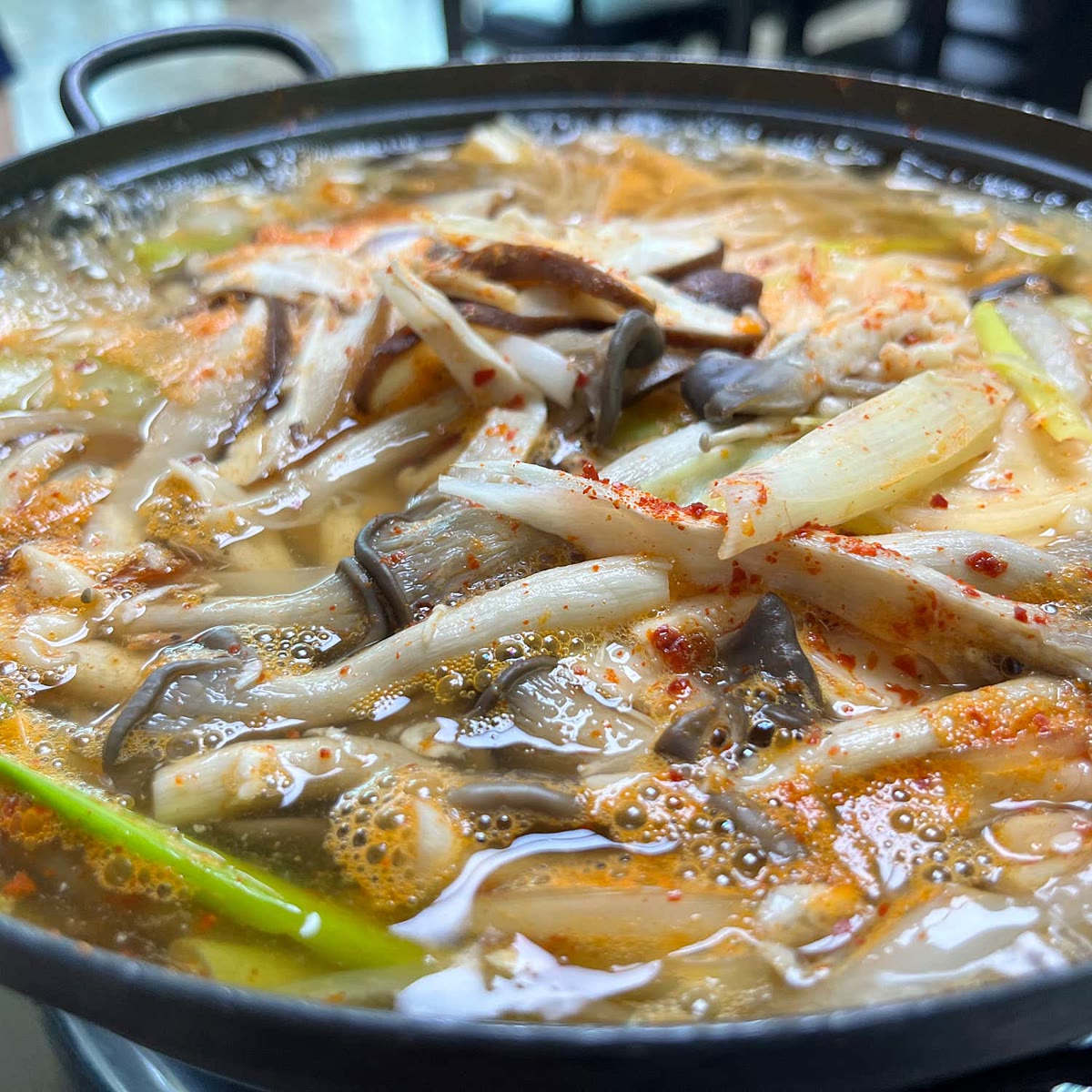 소이산두부촌 두부버섯전골이 끓는 모습, 표고버섯과 두부 사이로 국물이 우러나는 장면