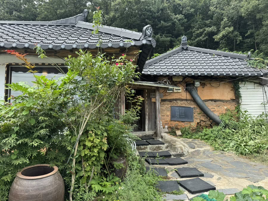 상궁전 한옥 외관, 검은 기와 지붕과 흙벽 사이로 돌계단 길이 이어지는 모습