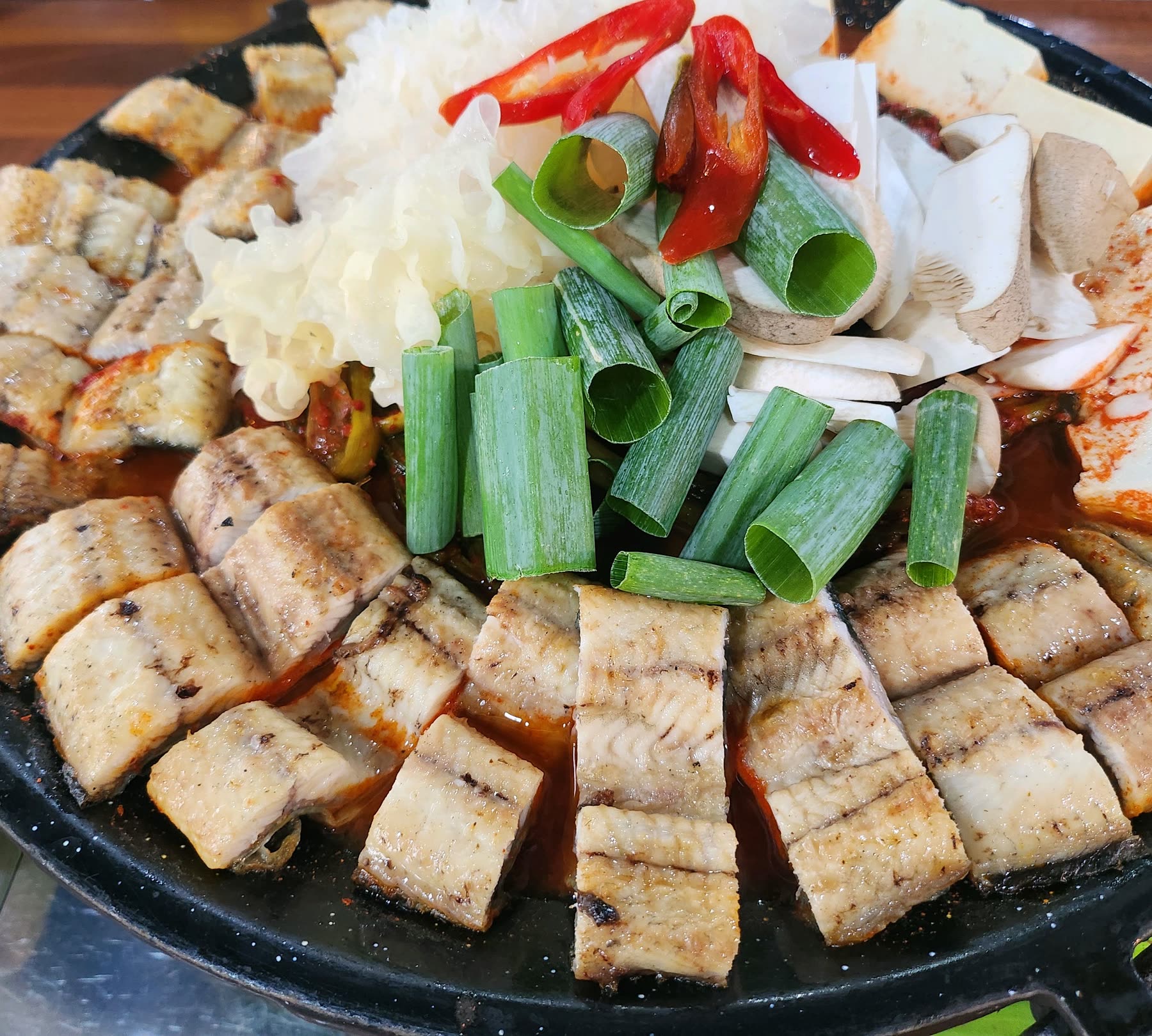 파김치장어전골 한 판, 장어 토막과 두부 둘레에 버섯과 대파가 올라간 모습