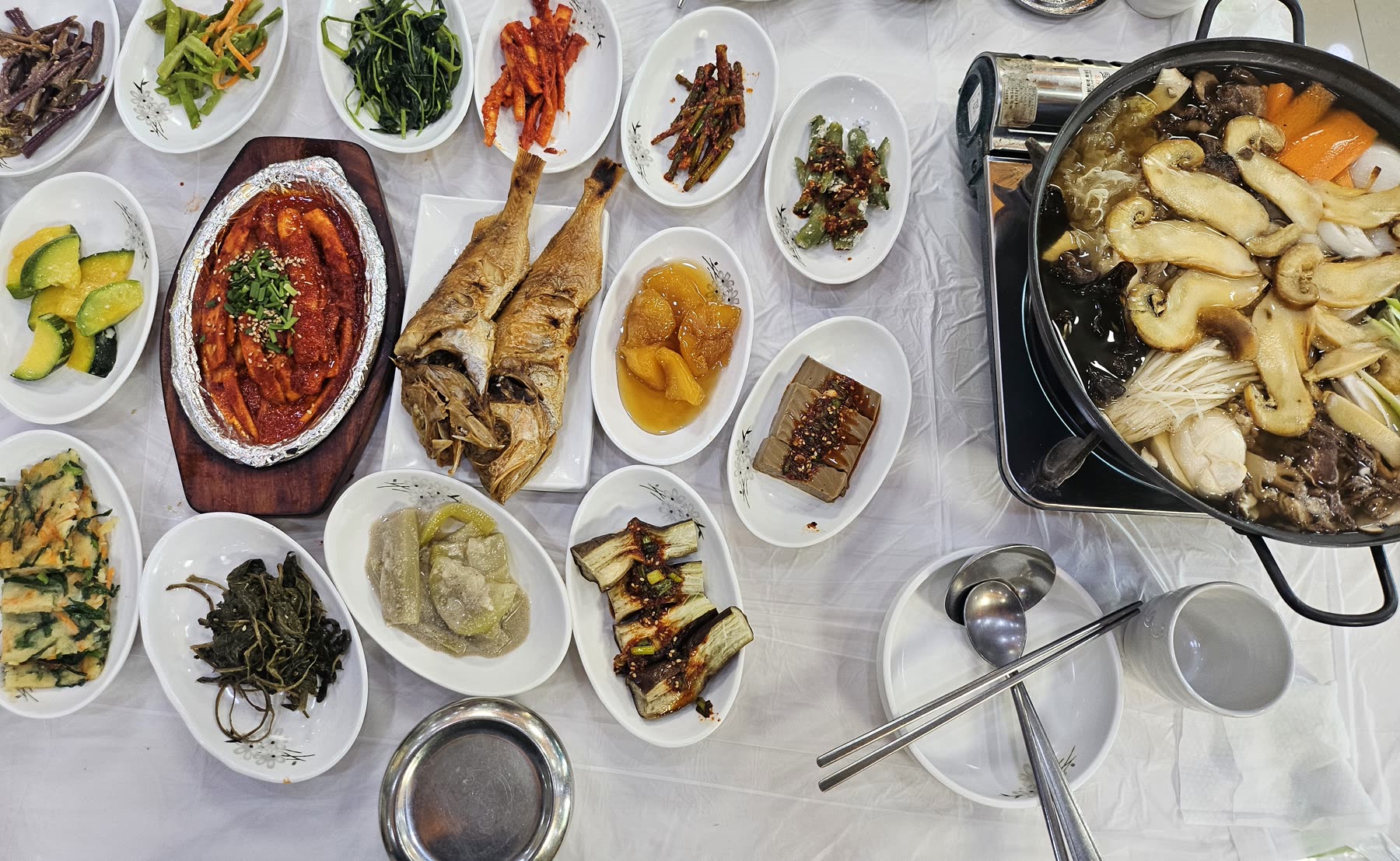 만남가든 상차림, 매콤한 양념 생선과 생선구이, 나물 반찬이 가득 깔린 테이블