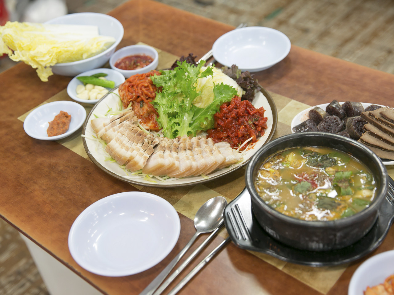 마포유가궁중족발 보쌈 상차림, 삶은 수육과 배추 김치 뚝배기 국물이 함께 차려진 모습