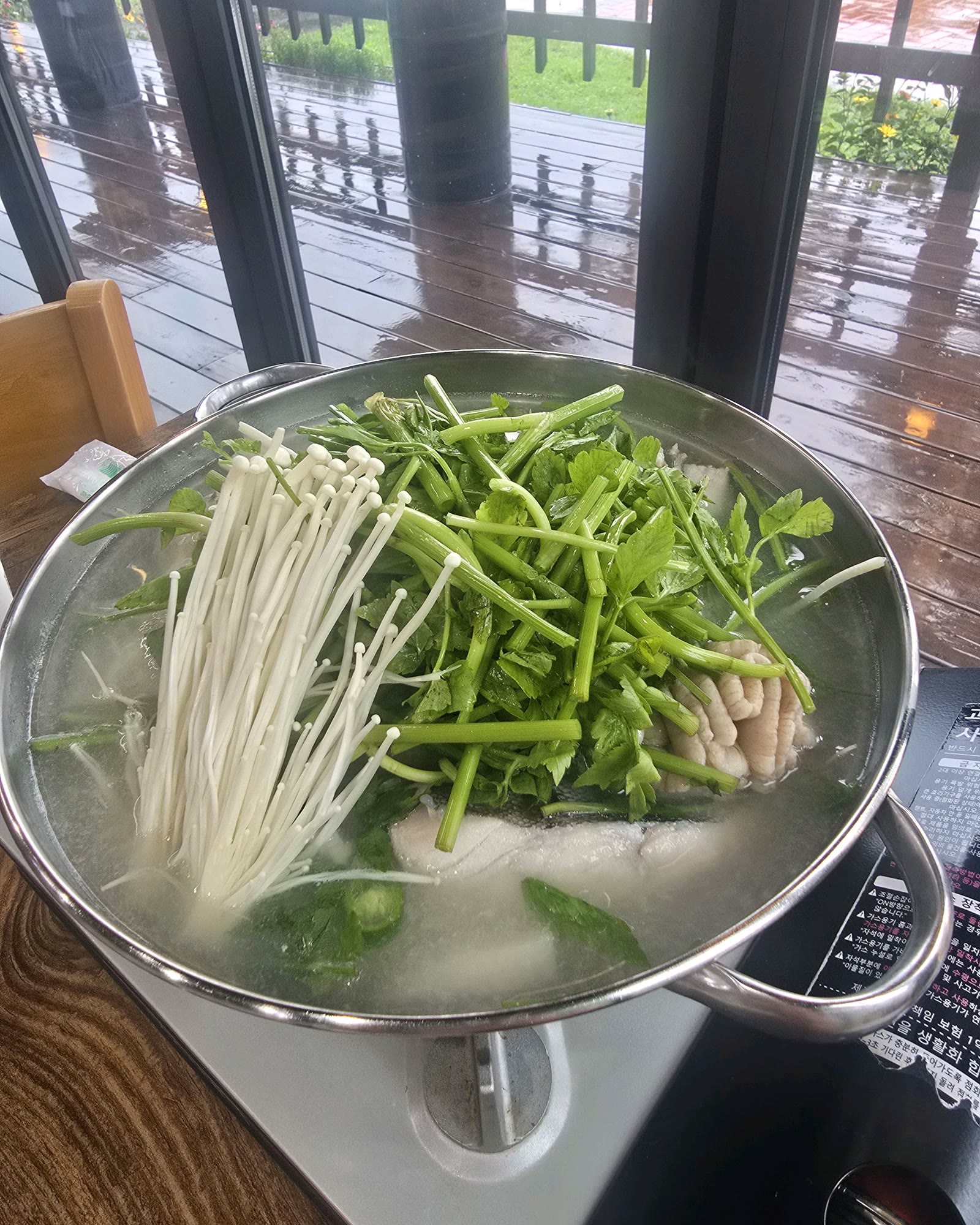 속초맛생대구탕 창가 자리에서 끓는 생대구탕 전골, 미나리와 팽이버섯이 가득한 모습
