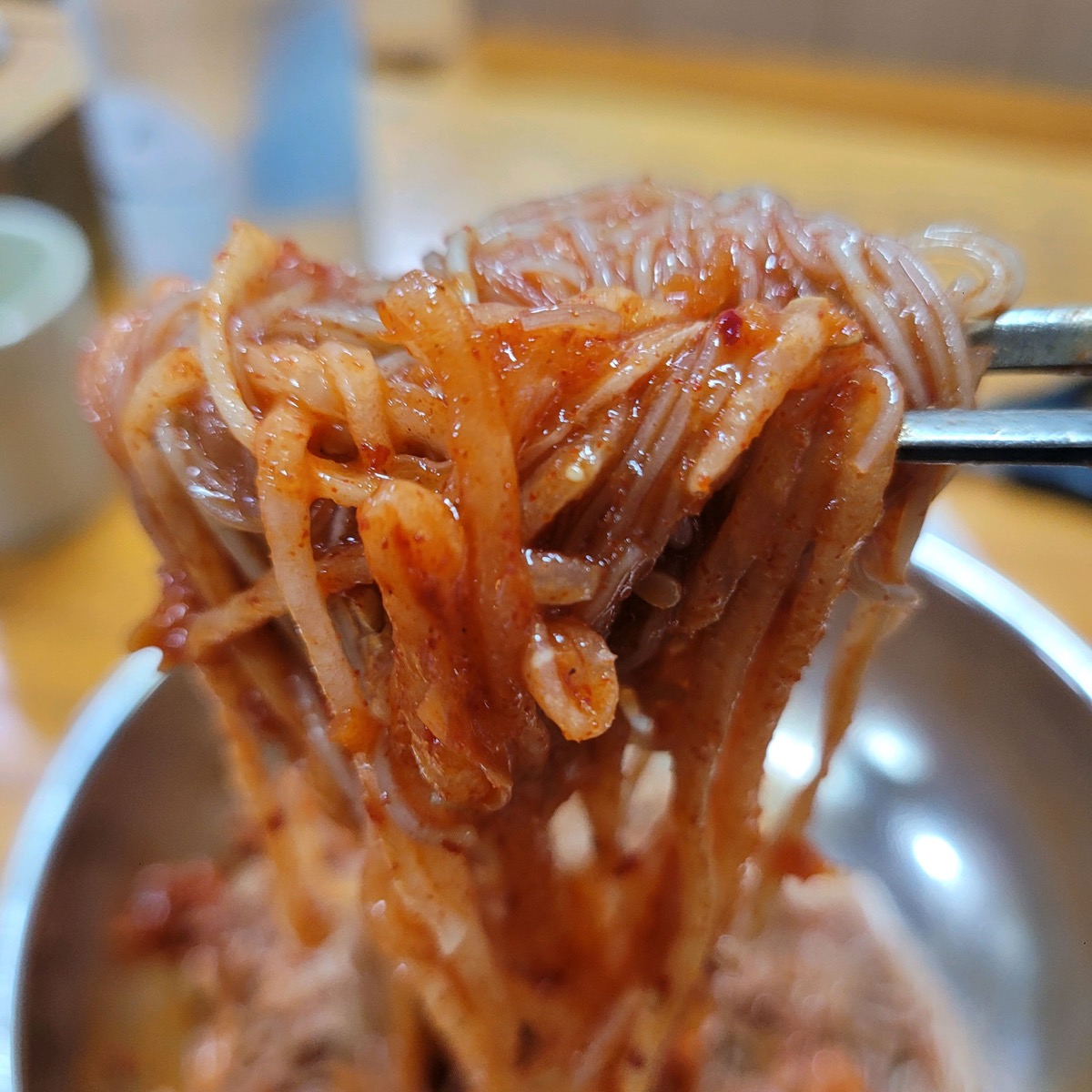 젓가락으로 들어 올린 자가제면 비빔냉면 면발