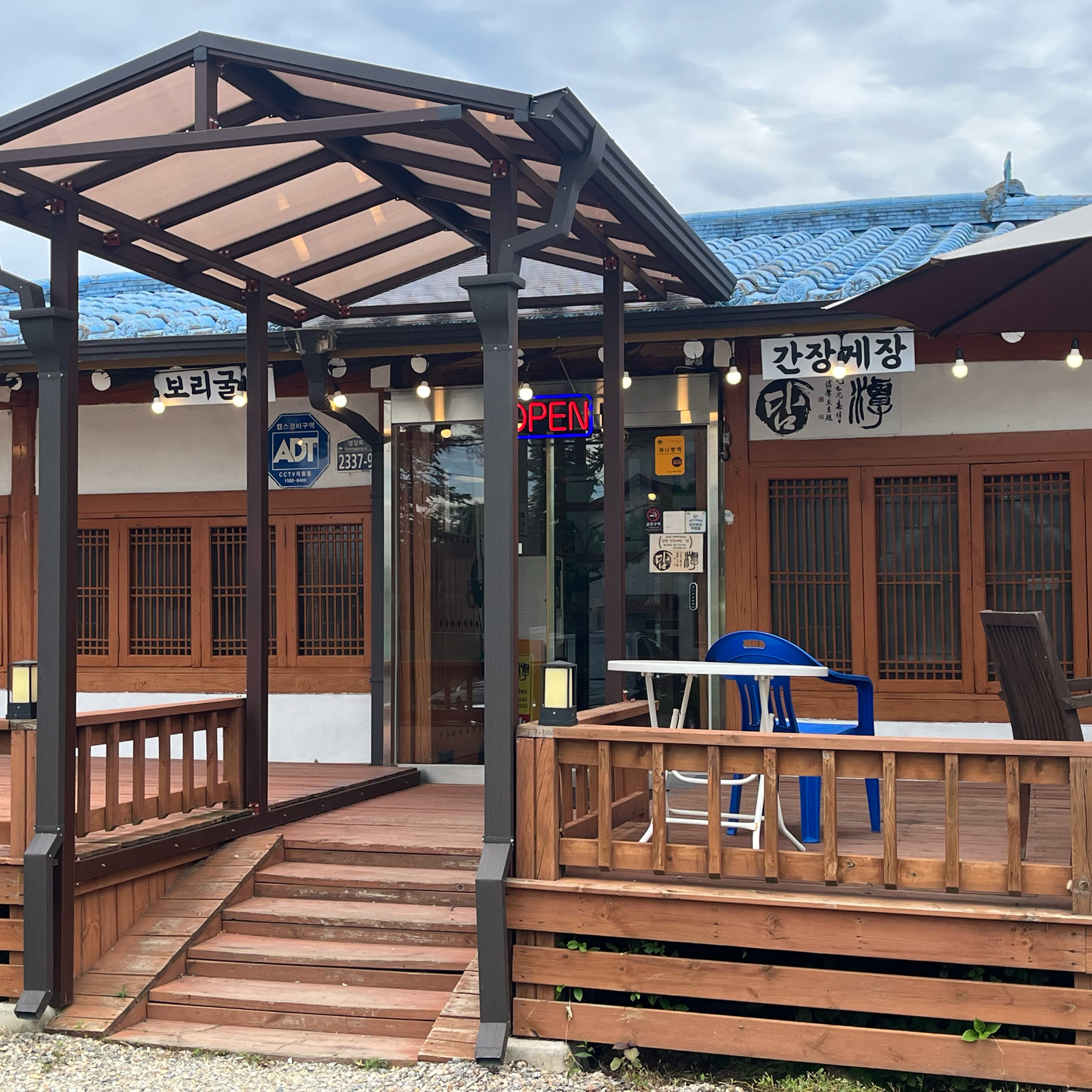 양평간장게장 담 외관, 파란 기와 지붕과 나무 데크, 간장게장 간판이 걸린 한옥 느낌 건물