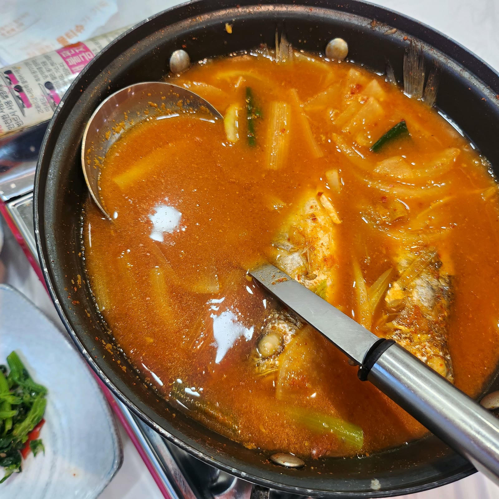 냄비 가득 끓고 있는 조기매운탕, 무와 대파가 들어가 국물이 빨갛게 우러난 모습