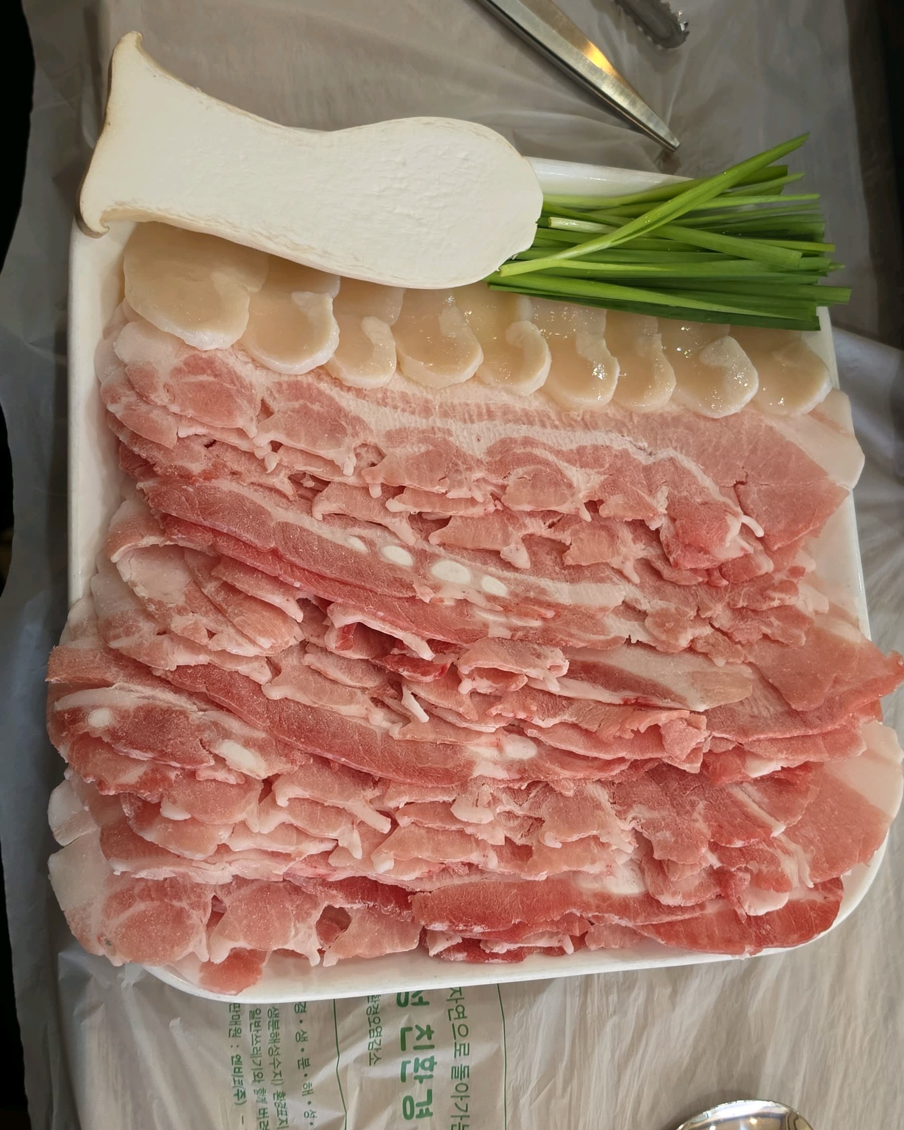 한려식당 대패삼겹살과 관자, 부추가 담긴 모둠 접시