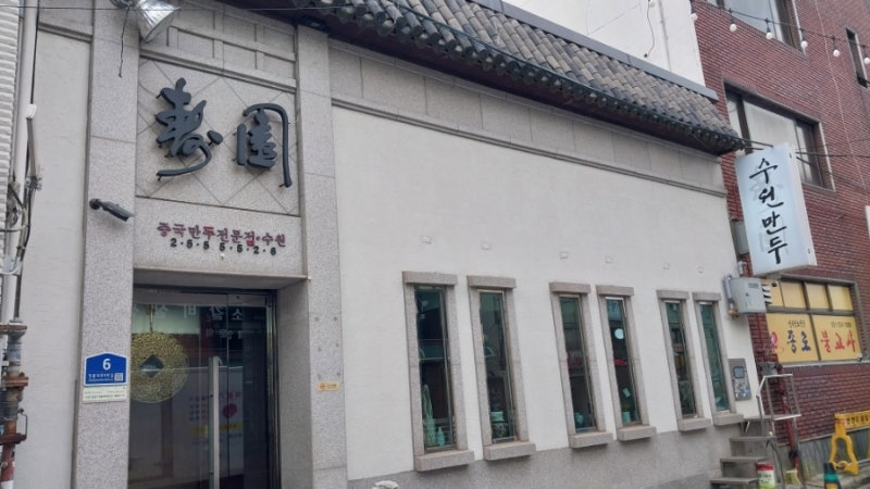 수원만두 외관, 壽園 한자 간판이 붙은 하얀 석조 건물과 세로 간판
